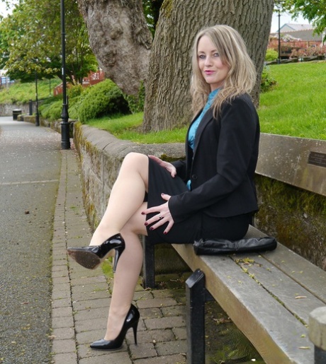 Fully clothed woman Kylie shows her shiny black pumps in hose on walkway 66570556