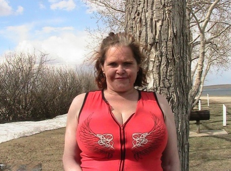 Older redhead Misha MILF displays her large tits by a lake before dildo riding 13545606