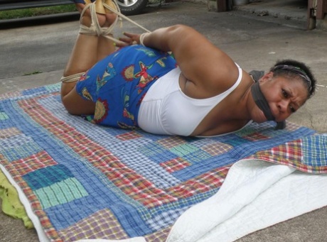 Mature ebony plumper is hogtied on a comforter while cleave gagged 17007594