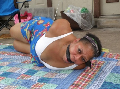 Mature ebony plumper is hogtied on a comforter while cleave gagged 17007594