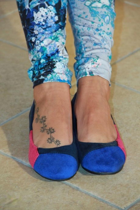 Fully clothed female frees her bare feet from flat shoes afore unlit fireplace 68094269