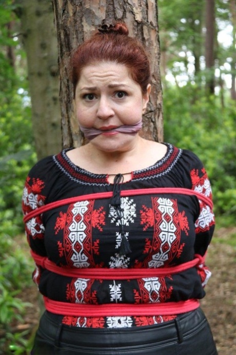 Thick redhead is cleave gagged and tied to a tree in a forest 16148455