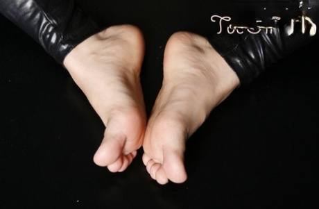 Caucasian female displays her painted toenails while wearing leather pants 36699137