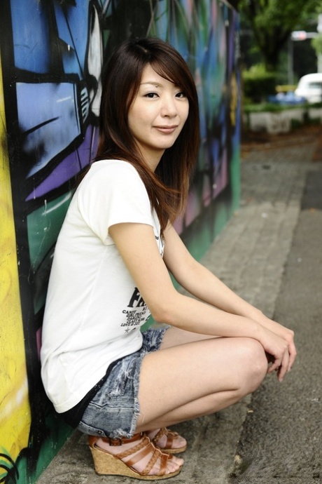 Japanese solo girl Tomomi Matsuda poses outdoors in a T-shirt and denim shorts 25650451